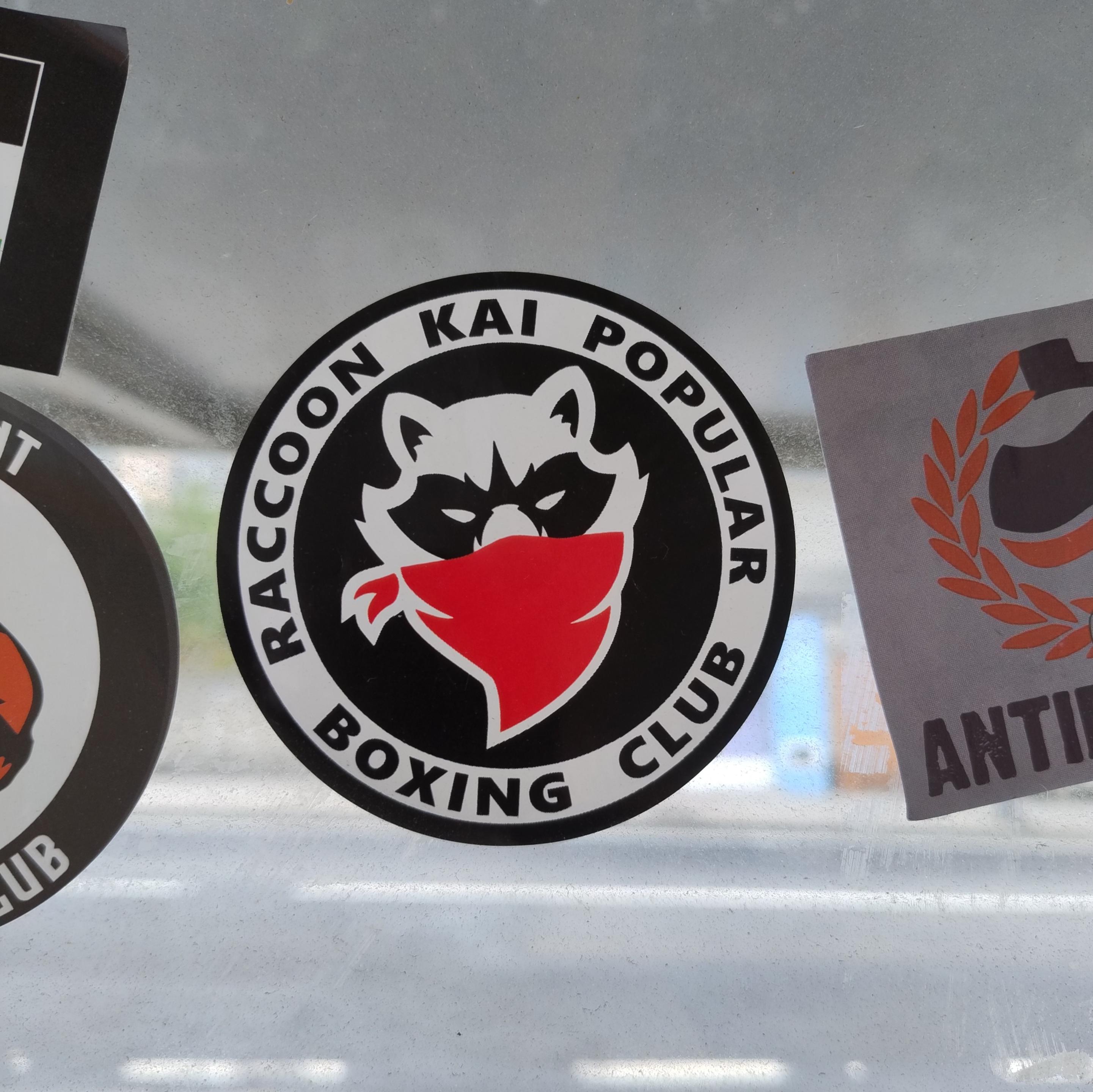Pegatina con el escudo de un club de artes marciales de París protagonizado por un mapache.