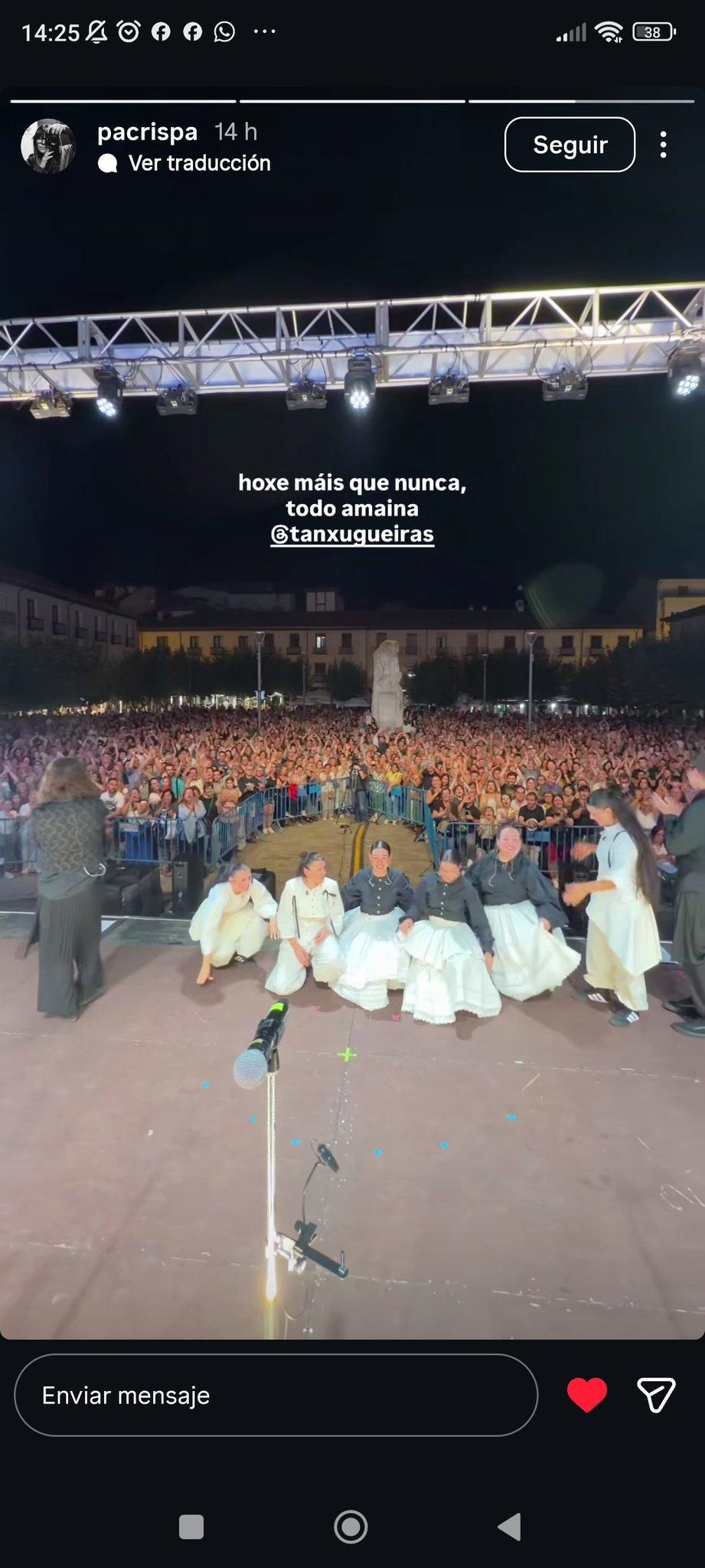 Una captura de pantalla de una historia de Instagram muestra un concierto nocturno al aire libre. En primer plano, un grupo de mujeres con trajes tradicionales baila en un escenario, mientras una multitud numerosa las observa. El texto superpuesto dice: "hoxe máis que nunca, todo amaina @tanxugueiras".